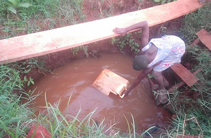 A young girl fetching water for home use at unclean well